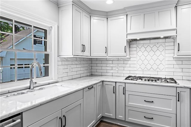 kitchen featuring a sink, gas cooktop, backsplash, light stone counters, and recessed lighting