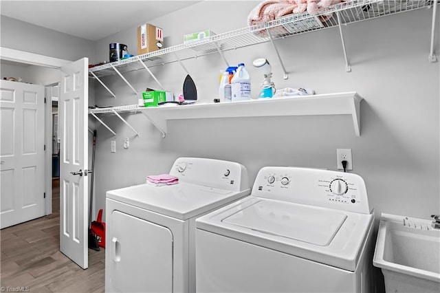 clothes washing area with washing machine and dryer and light wood finished floors