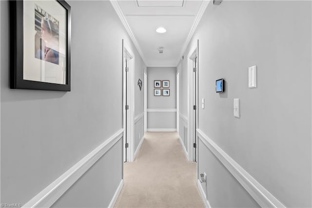 hallway featuring crown molding, light colored carpet, and baseboards