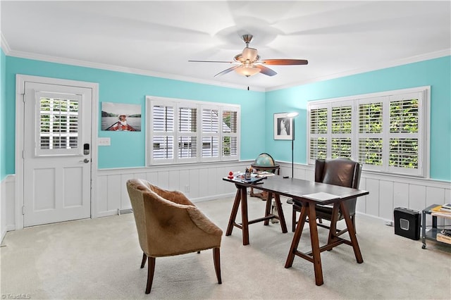 office space featuring crown molding, light colored carpet, a wainscoted wall, plenty of natural light, and ceiling fan