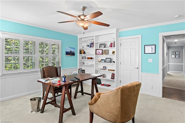 office featuring light colored carpet, a wainscoted wall, ceiling fan, crown molding, and a decorative wall