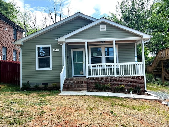 bungalow featuring fence, stairs, a porch, a front yard, and crawl space