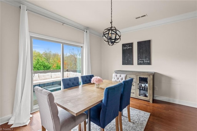 dining space with dark hardwood / wood-style flooring, an inviting chandelier, and ornamental molding