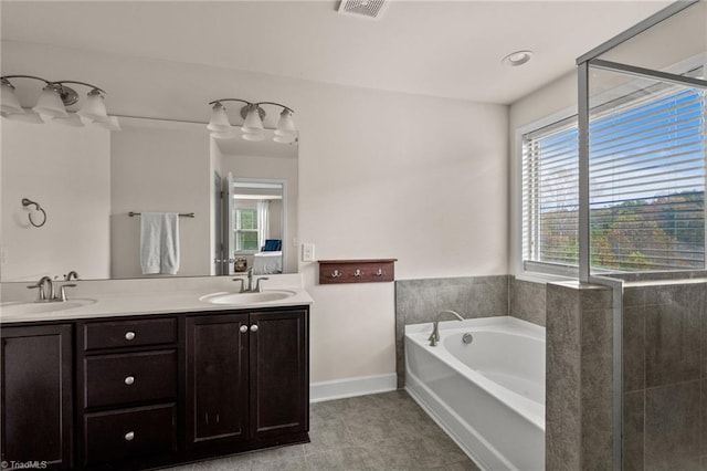 bathroom with tile patterned floors, a tub, and vanity