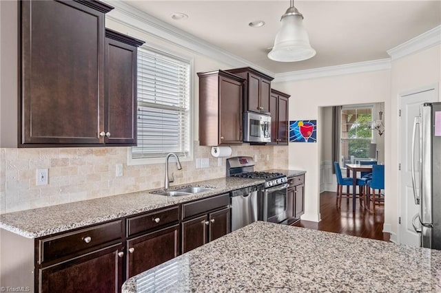 kitchen with pendant lighting, sink, light stone countertops, ornamental molding, and stainless steel appliances