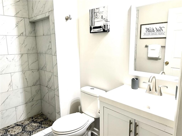 full bath featuring tiled shower, vanity, and toilet