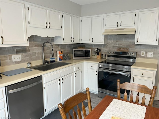 kitchen with under cabinet range hood, white cabinetry, appliances with stainless steel finishes, and a sink