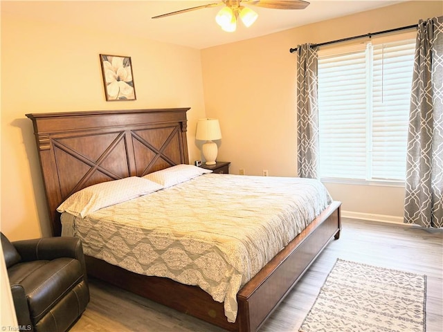 bedroom with ceiling fan, multiple windows, wood finished floors, and baseboards