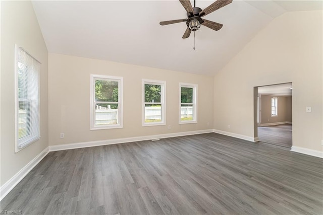 unfurnished room with vaulted ceiling, ceiling fan, a wealth of natural light, and dark hardwood / wood-style floors