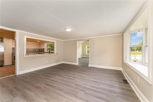 unfurnished living room with hardwood / wood-style flooring and crown molding