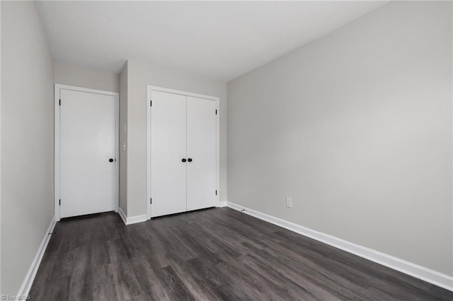 unfurnished bedroom featuring dark hardwood / wood-style flooring and a closet