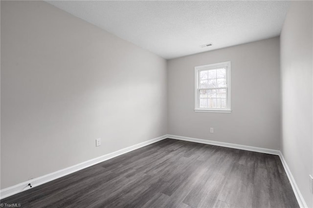 empty room with dark hardwood / wood-style floors and a textured ceiling