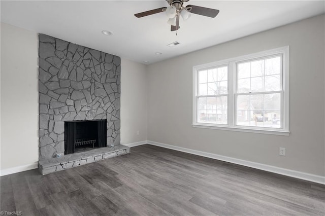 unfurnished living room featuring ceiling fan, a stone fireplace, and dark hardwood / wood-style flooring