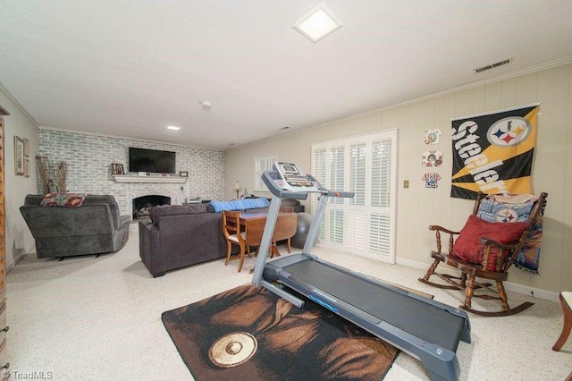 workout area featuring a brick fireplace, brick wall, crown molding, and carpet flooring