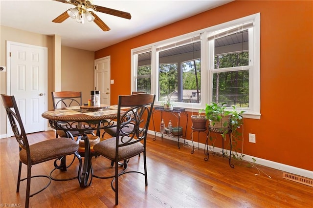 dining space featuring baseboards, a ceiling fan, and wood finished floors