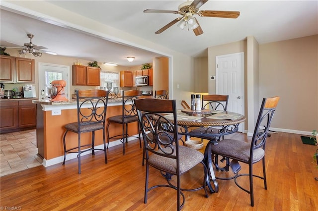 dining space featuring light wood finished floors, baseboards, and ceiling fan
