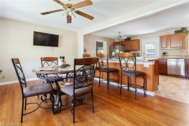 dining area with ceiling fan, baseboards, and light wood-type flooring