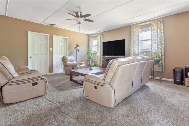 carpeted living area with a ceiling fan and baseboards