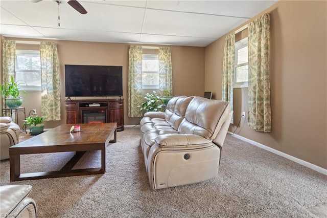 living area featuring carpet, baseboards, a ceiling fan, and plenty of natural light