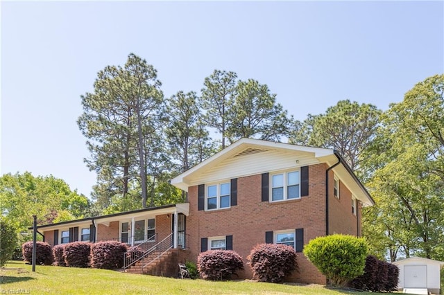 view of front of home featuring brick siding, a front lawn, a storage shed, and an outdoor structure