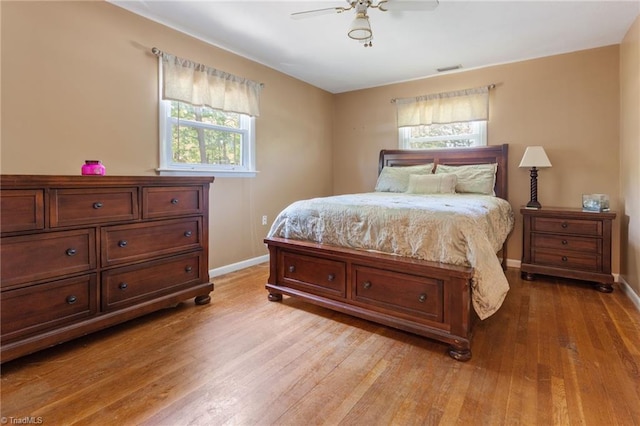 bedroom featuring baseboards, a ceiling fan, wood finished floors, and visible vents