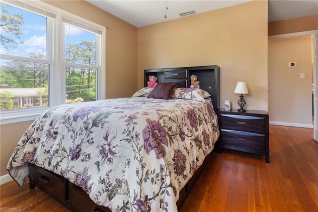 bedroom with baseboards, wood finished floors, and visible vents