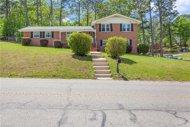tri-level home featuring a front lawn and brick siding