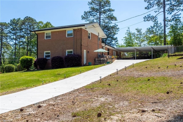 view of side of home featuring a lawn, an attached carport, concrete driveway, and brick siding
