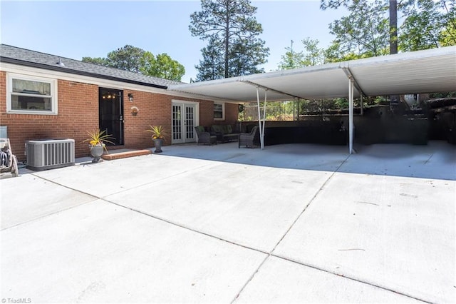 exterior space with french doors, a carport, central AC unit, driveway, and brick siding