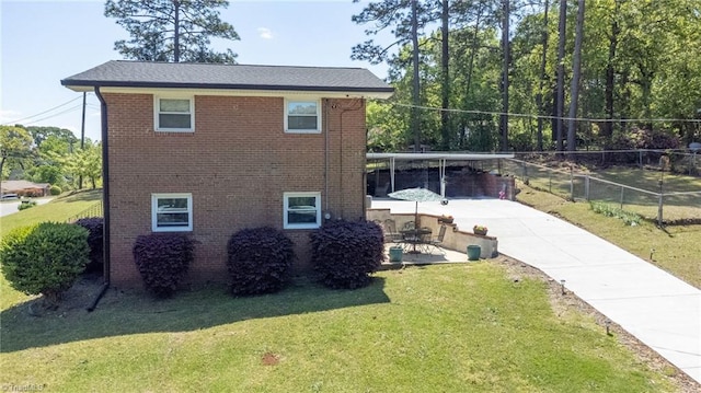 view of property exterior with concrete driveway, brick siding, and a yard