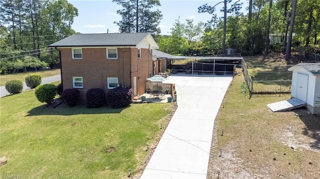 view of side of property with a lawn, a carport, concrete driveway, and fence
