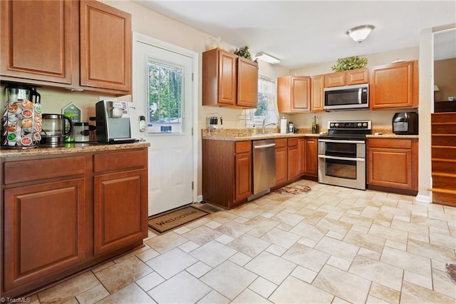kitchen featuring brown cabinetry, appliances with stainless steel finishes, a sink, and light countertops