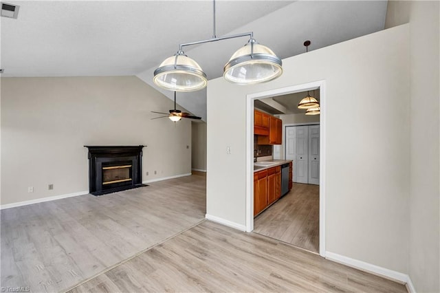 unfurnished living room with visible vents, a fireplace with flush hearth, vaulted ceiling, light wood-style flooring, and a ceiling fan