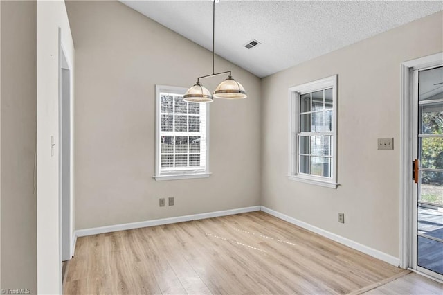 unfurnished dining area with visible vents, a textured ceiling, wood finished floors, baseboards, and vaulted ceiling