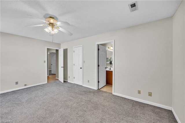 unfurnished bedroom with ensuite bath, light colored carpet, visible vents, and baseboards