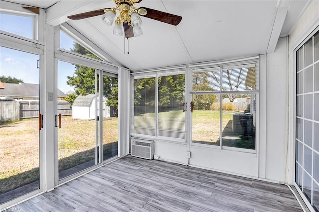 unfurnished sunroom with vaulted ceiling, a ceiling fan, and a wall mounted air conditioner