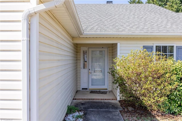 entrance to property featuring roof with shingles