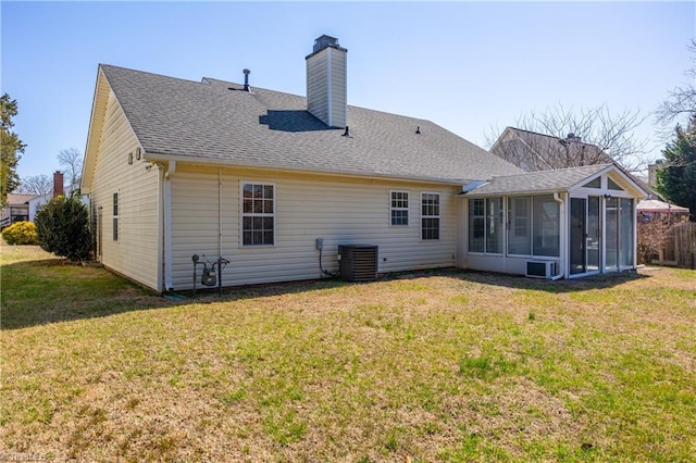 rear view of house with cooling unit, a shingled roof, a yard, and a sunroom