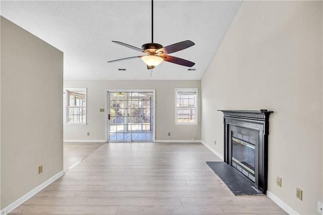 unfurnished living room with a fireplace with flush hearth, wood finished floors, visible vents, and ceiling fan