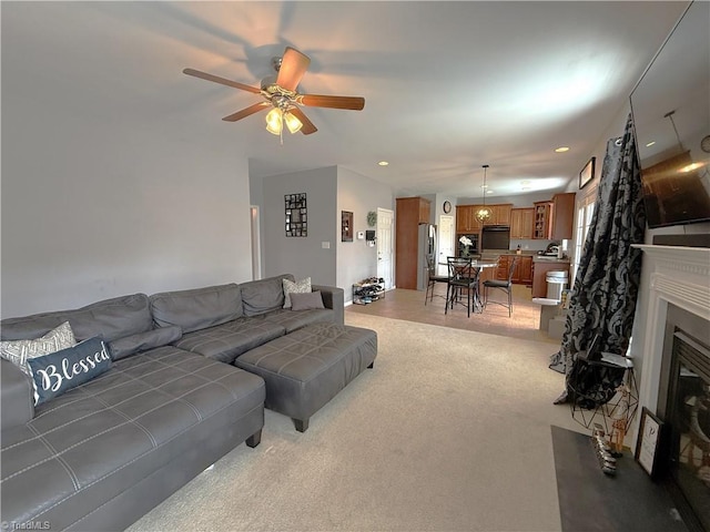 living area with light carpet, a glass covered fireplace, a ceiling fan, and recessed lighting