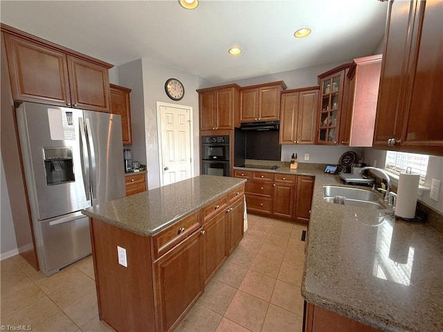 kitchen featuring brown cabinets, a kitchen island, a sink, under cabinet range hood, and black appliances