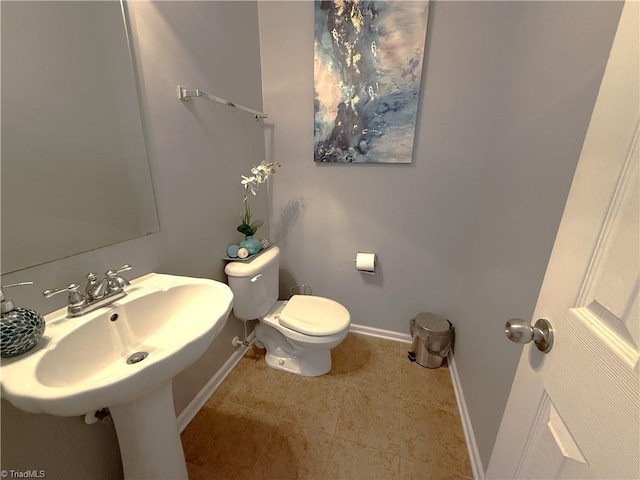 bathroom with tile patterned flooring, baseboards, a sink, and toilet