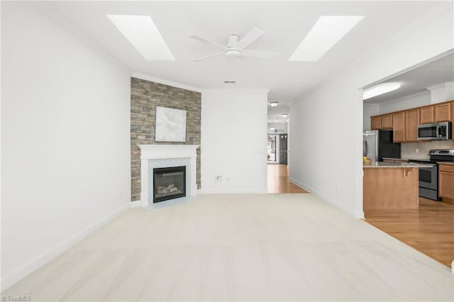 6924 Langdon Village Ct, Clemmons, NC 27012 - unfurnished living room featuring crown molding, a skylight, ceiling fan, a large fireplace, and light carpet