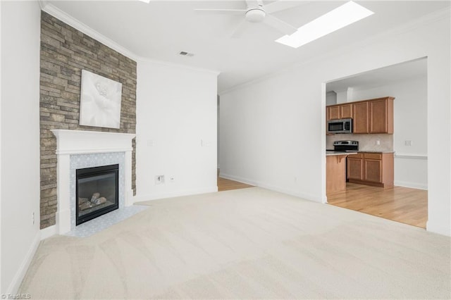 6924 Langdon Village Ct, Clemmons, NC 27012 - unfurnished living room featuring ornamental molding, a ceiling fan, light carpet, a skylight, and a fireplace