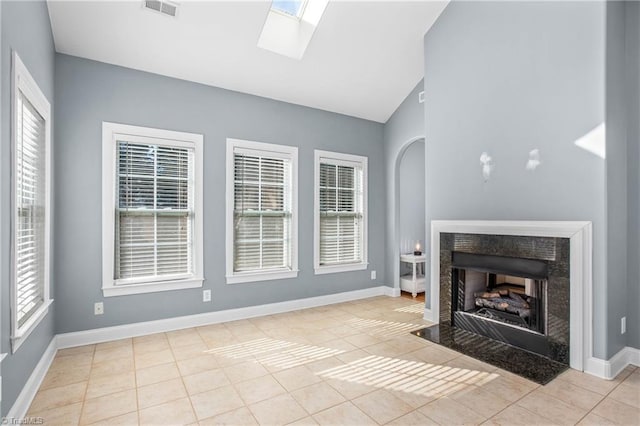 unfurnished living room featuring lofted ceiling with skylight and light tile patterned floors