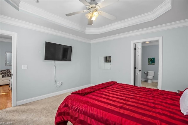 carpeted bedroom featuring crown molding, ensuite bath, a raised ceiling, and ceiling fan