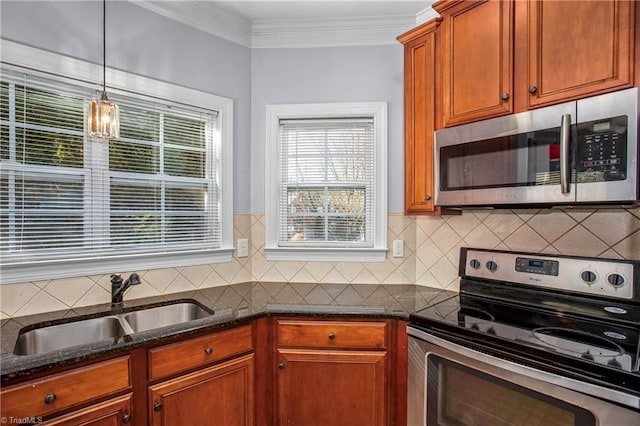 kitchen featuring sink, crown molding, decorative light fixtures, dark stone countertops, and appliances with stainless steel finishes