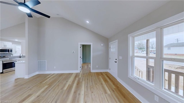 unfurnished living room with ceiling fan, high vaulted ceiling, sink, and light hardwood / wood-style floors