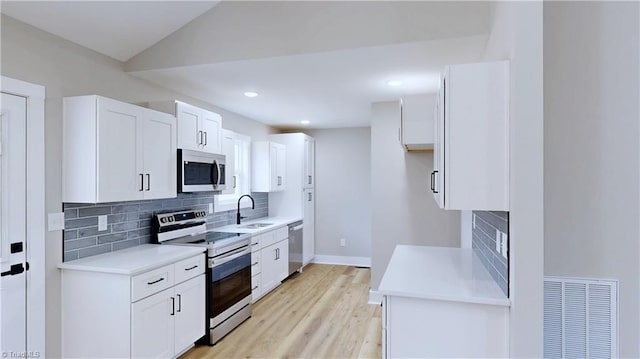 kitchen with white cabinetry, sink, light wood-type flooring, and appliances with stainless steel finishes