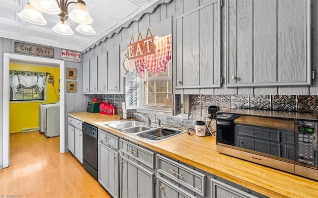 kitchen featuring gray cabinetry, sink, light hardwood / wood-style flooring, independent washer and dryer, and black dishwasher